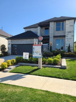 A modern two-story brick home with manicured landscaping in Painted Tree by Trophy Signature Homes (McKinney, TX).
