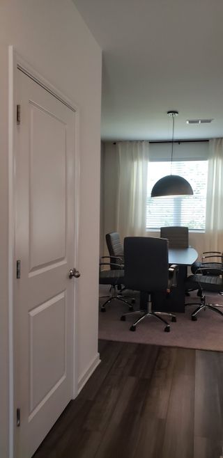A modern dining area with sleek chairs, a round table, and a large pendant light, complemented by soft natural light.