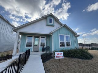 Street view A charming blue and white home with a welcoming porch in Garten Haus Cottages At Solms Landing by Wes Peoples Homes (New Braunfels, TX).