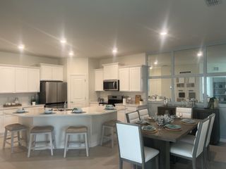 Modern kitchen with a sleek island, white cabinets, stainless steel appliances, and an adjoining dining area set for a meal.