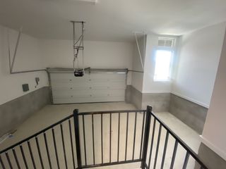 A spacious garage with a window, modern garage door opener, and sleek metal railing.