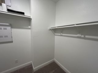 Model Home A spacious walk-in closet with neutral walls, white shelving, and soft carpet, offering ample storage space.