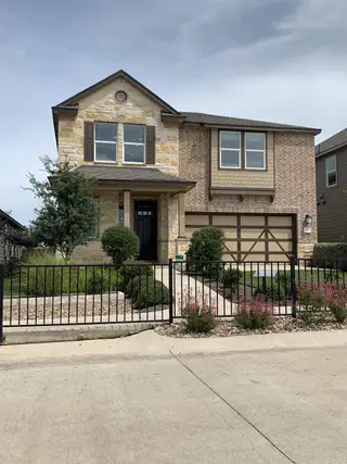 Street view A charming stone and brick home with landscaped front yard in Sonterra - Cool Water by KB Home (Jarrell, TX).