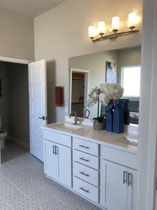 A chic bathroom featuring a dual-sink vanity, geometric floor tiles, and elegant lighting.