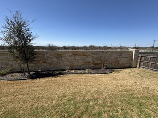Street view A tranquil backyard with a stone wall and young trees in Mesa Western by Chesmar Homes (Cibolo, TX).