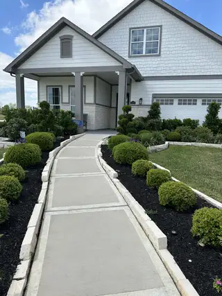 Street view A charming gray and white home with manicured shrubs in Winfrey Estates by ROC Homes (Tomball, TX).