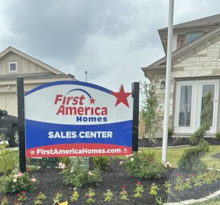A welcoming sales center for First America Homes in Meadow Park, Conroe, TX, with well-kept gardens and inviting architecture.