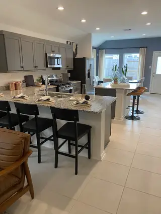 A modern kitchen with sleek gray cabinets, granite countertops, and a cozy dining area by the window.