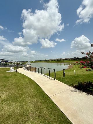 Scenic walkway with lush landscaping and serene pond views in Del Webb Fulshear by Del Webb (Fulshear, TX).