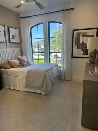 A cozy bedroom featuring a comfy bed, elegant arched windows, neutral decor, and stylish artwork for a relaxing retreat.