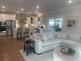 An open, inviting living area with a plush sectional, modern kitchen, and cozy decor, perfect for relaxation and entertaining.