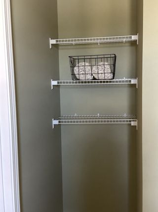 A neat closet with wire shelving and a basket of rolled towels, perfect for organized storage.