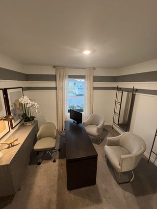 A cozy office with a sleek desk, comfy chairs, and stylish decor, featuring modern striped walls and soft lighting.