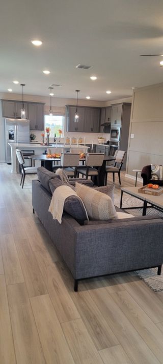 An open-concept living area with modern gray cabinetry, cozy seating, and elegant dining space, perfect for entertaining.