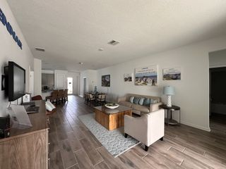 A contemporary living space with a neutral-toned sofa, modern décor, and an open-concept kitchen.