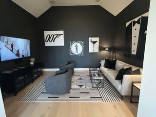 A bold and sophisticated entertainment space with a James Bond-inspired design, black walls, and comfortable seating for movie nights.