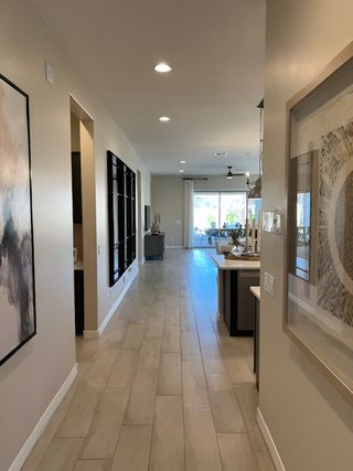 An elegant hallway with tile flooring, modern art, and recessed lighting leading to a bright living area.
