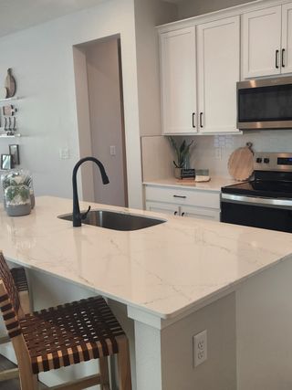 Model Home A modern kitchen with sleek white cabinets, marble countertops, and stylish pendant lighting, blending elegance with functionality.