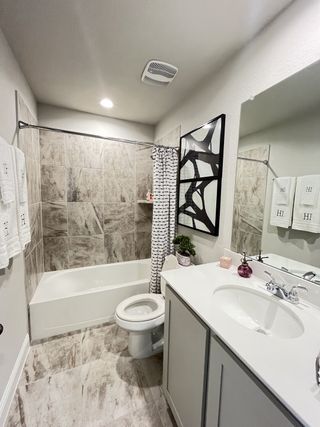Model Home A chic bathroom with marble-tiled shower, sleek white vanity, and modern decor accents.