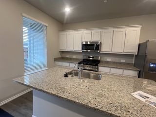 A modern kitchen with sleek granite countertops, white cabinetry, and stainless steel appliances.