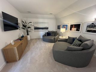 A cozy media room with plush seating, modern decor, and artwork, creating an inviting entertainment space.