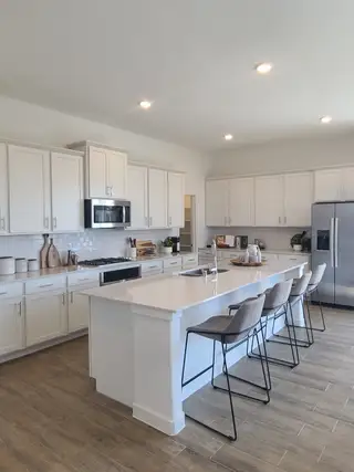 Model Home A modern kitchen with sleek white cabinetry, an island, and stainless steel appliances.