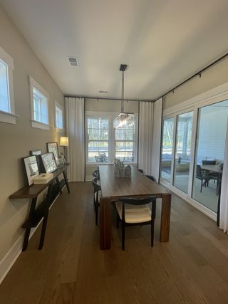 A cozy dining room featuring a wooden table, chic lighting, and large windows with elegant drapes.