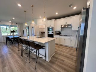 Model Home A sleek and modern kitchen with white cabinetry, pendant lighting, and a large island perfect for entertaining.
