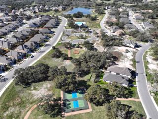 Aerial view of 6 Creeks by Coventry Homes in Kyle, TX, showcasing landscaped community with tennis courts, lake, and pool.