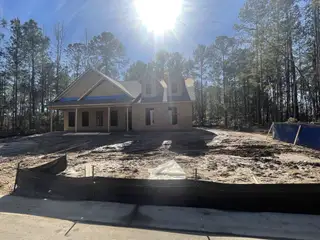 Street view A charming new construction home in Carolina Bay by Center Park Homes, nestled against a backdrop of trees in Ridgeville, SC.