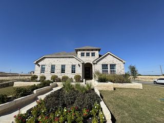 Street view A beautiful stone exterior home with manicured landscaping in Hunters Glen by Brightland Homes (Jarrell, TX).