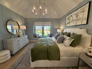 A serene bedroom with vaulted ceilings, soft green accents, and a charming window seat, creating a peaceful and inviting atmosphere.