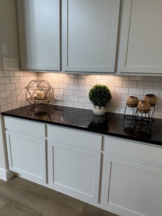 A modern kitchen counter with sleek white subway tile backsplash, dark countertop, and elegant decor accents.