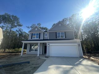 A charming two-story gray home with a porch and spacious garage in Ashley Cove by Eastwood Homes (Summerville, SC).