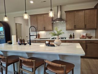 Model Home A modern kitchen with a sleek island, warm wood cabinets, pendant lighting, and stylish seating.