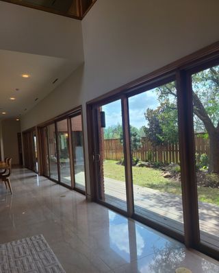 A bright hallway featuring floor-to-ceiling windows, glossy tile flooring, and views of a serene backyard.