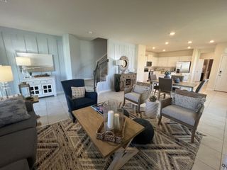 Model Home A stylish open-concept living area with cozy seating, neutral tones, and natural light flowing in through large windows.