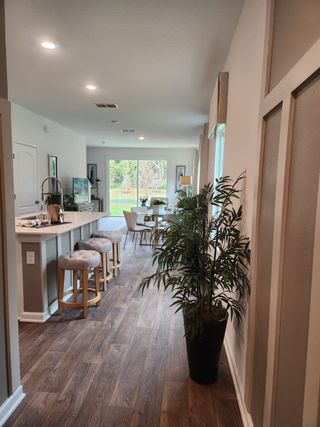 A cozy kitchen and dining area with wood flooring, bar stools, and large windows overlooking a lush view.