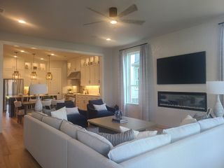 A cozy living area with large sectional sofa, modern fireplace, and an open kitchen featuring pendant lights and chic cabinetry.
