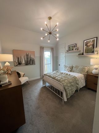 A cozy bedroom with chic lighting, a soft carpet, and stylish decor, creating a peaceful retreat.