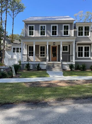 A charming gray home with a spacious porch in The Preserve at Pennys Creek by Brightwater Homes (Johns Island, SC).