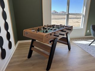 Model Home A modern game room featuring a sleek foosball table, stylish decor, and large window for natural light.