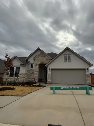 Street view A modern home with stone accents and manicured lawn in Lariat by Chesmar Homes (Liberty Hill, TX).