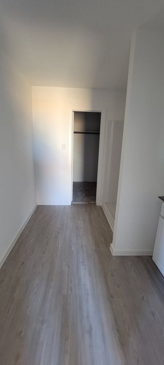 A bright, minimalist hallway with sleek wood flooring and an open closet space.