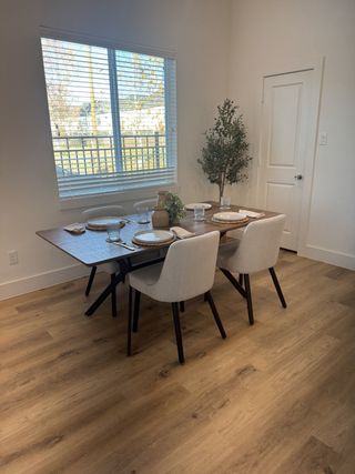 A cozy dining area with a chic wooden table, modern chairs, and a sunlit window, complemented by a small indoor plant.