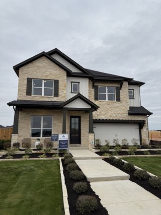 Street view A charming stone facade home with a lush yard in Barksdale by M/I Homes (Leander, TX).