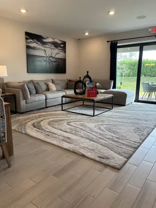 Model Home A contemporary living room with a cozy sectional, abstract rug, modern art, and expansive glass doors to the patio.
