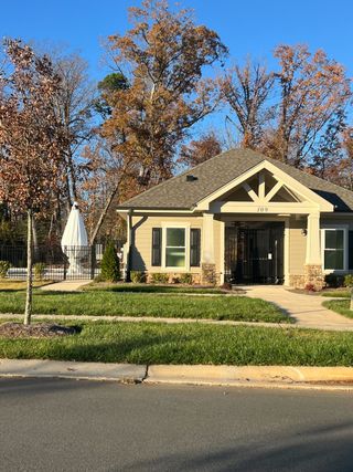 A charming clubhouse with a manicured lawn in Calvin Creek by D.R. Horton, set amidst picturesque trees in Troutman, NC.