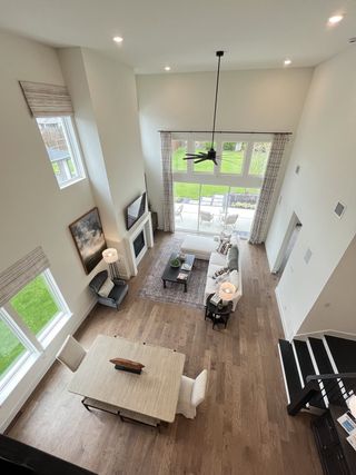 Model Home A bright, airy living room with high ceilings, large windows, cozy seating, and a modern dining area.