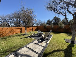 A serene backyard with Adirondack chairs, a fire pit, and lush landscaping.